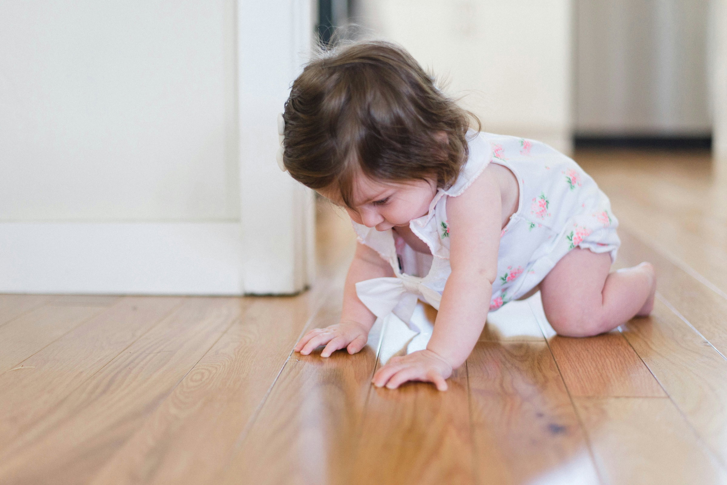 A baby crawling across a warm wooden floor