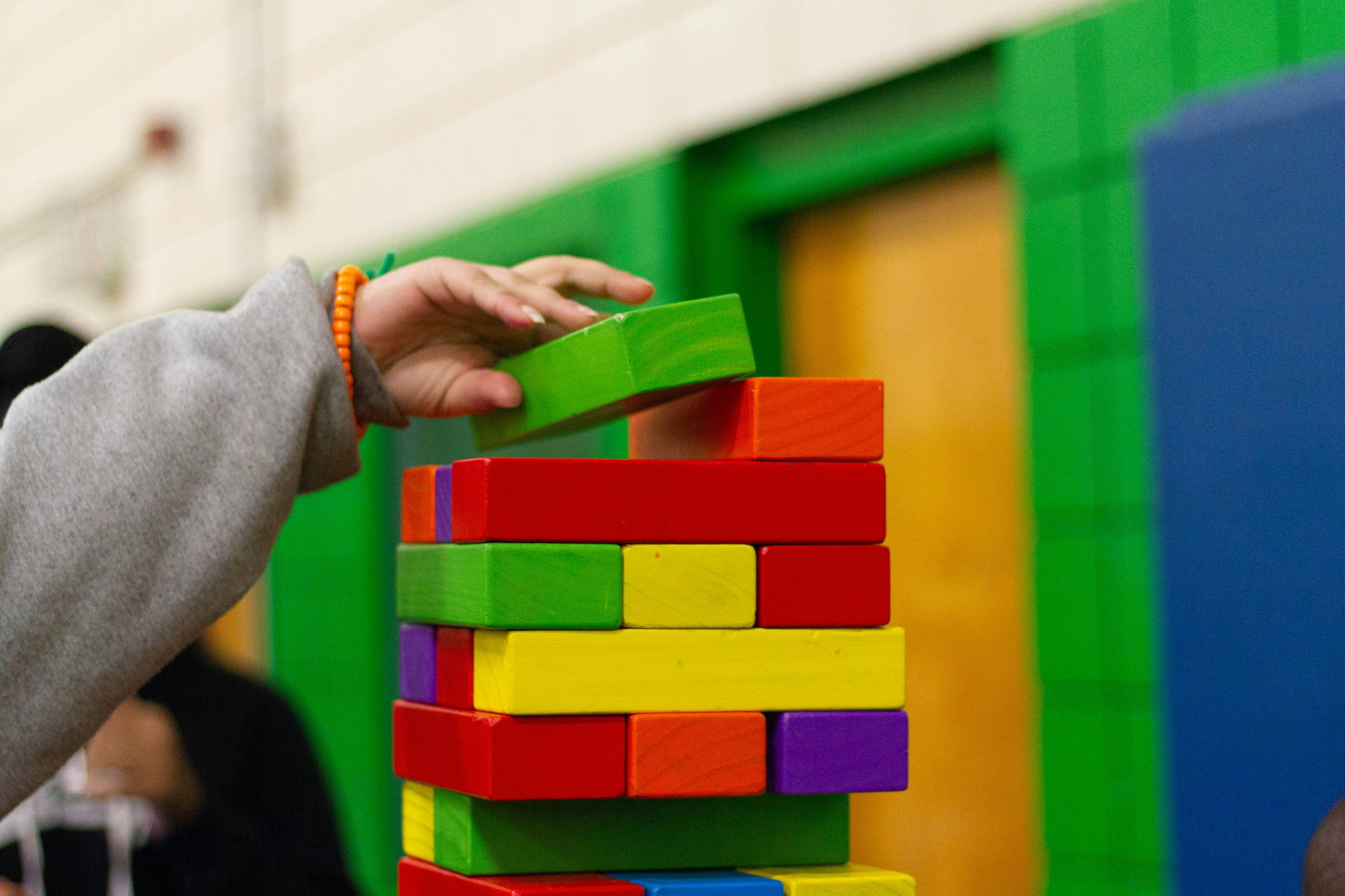 A child stacking colourful wooden blocks into a tall tower