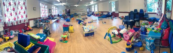 A community hall set up for a Stay & Play session, with ride-ons, play mats and toys laid out ready to welcome families