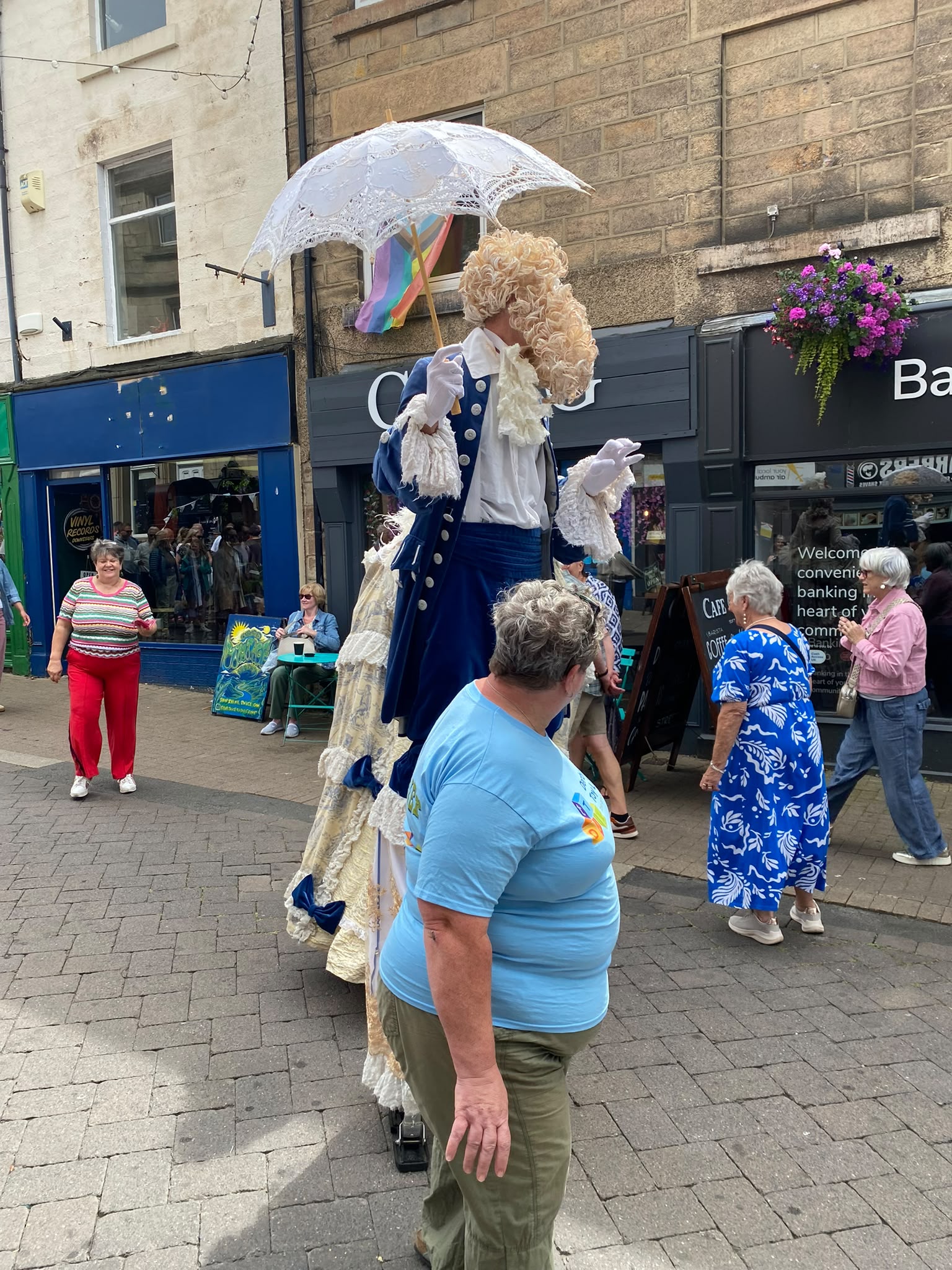 Two stilt walkers in elaborate period costume, a "gentleman" and a "lady", performing on the high street